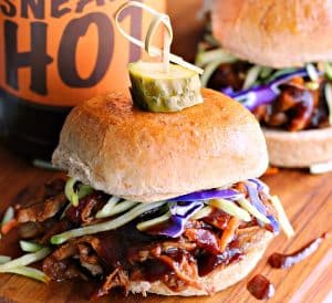 slow cooker beer braised pulled pork ~ 3 pulled pork sliders topped with confetti slaw and a dill pickle disc.