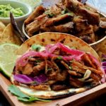 carnitas taco in flour tortilla with bowl of carnitas also shown