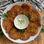white plate with golden polish potato pancakes and bowl of sour cream