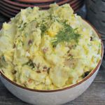white bowl with Deviled Egg Potato Salad garnished with fresh dill