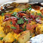 cubed potatoes topped with melted cheese and bacon in an open foil packet