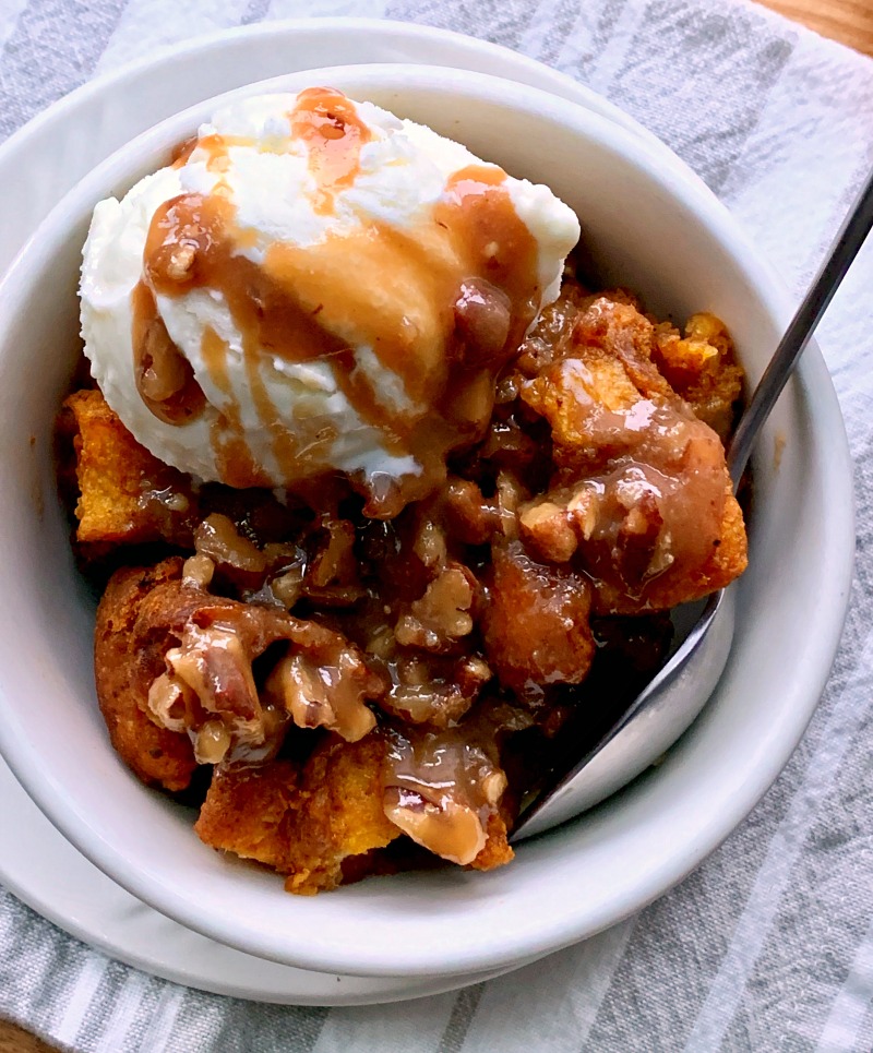 Bowl of Pumpkin Bread Pudding topped with vanilla ice cream and drizzled with praline sauce