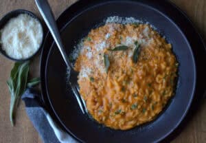 black bowl with pumpkin rice (risotto) sprinkled with parmesan cheese