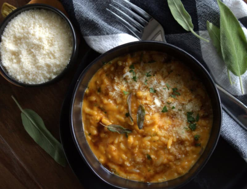 black bowl with pumpkin rice (risotto) garnished with crispy sage leaves