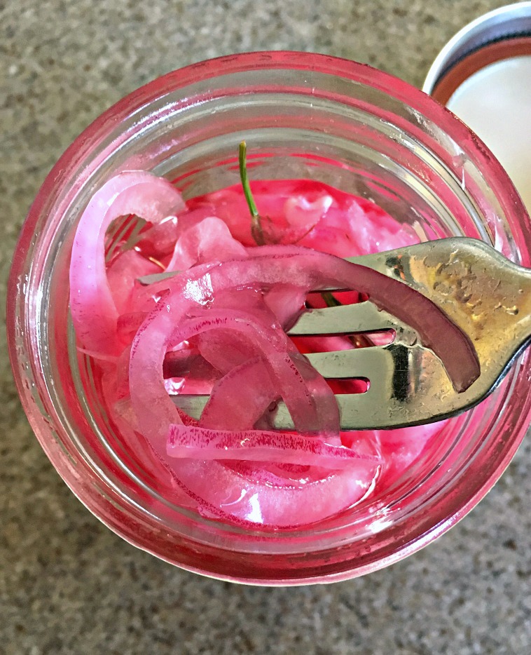 overhead view of onions in mason jar being lifted with a fork