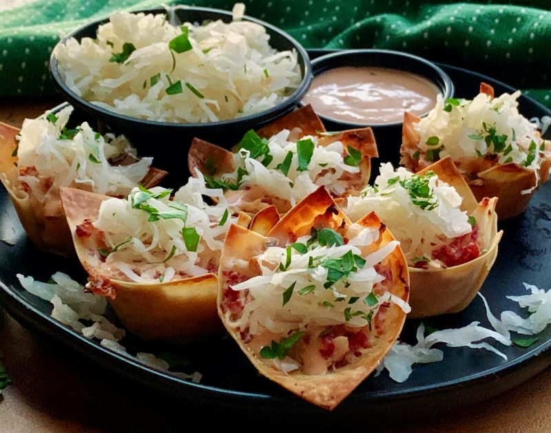 black plate with reuben wonton cups garnished with parsley