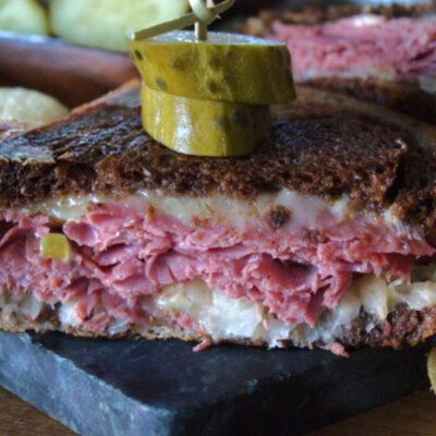 sliced reuben sandwich with pickles and potato chips