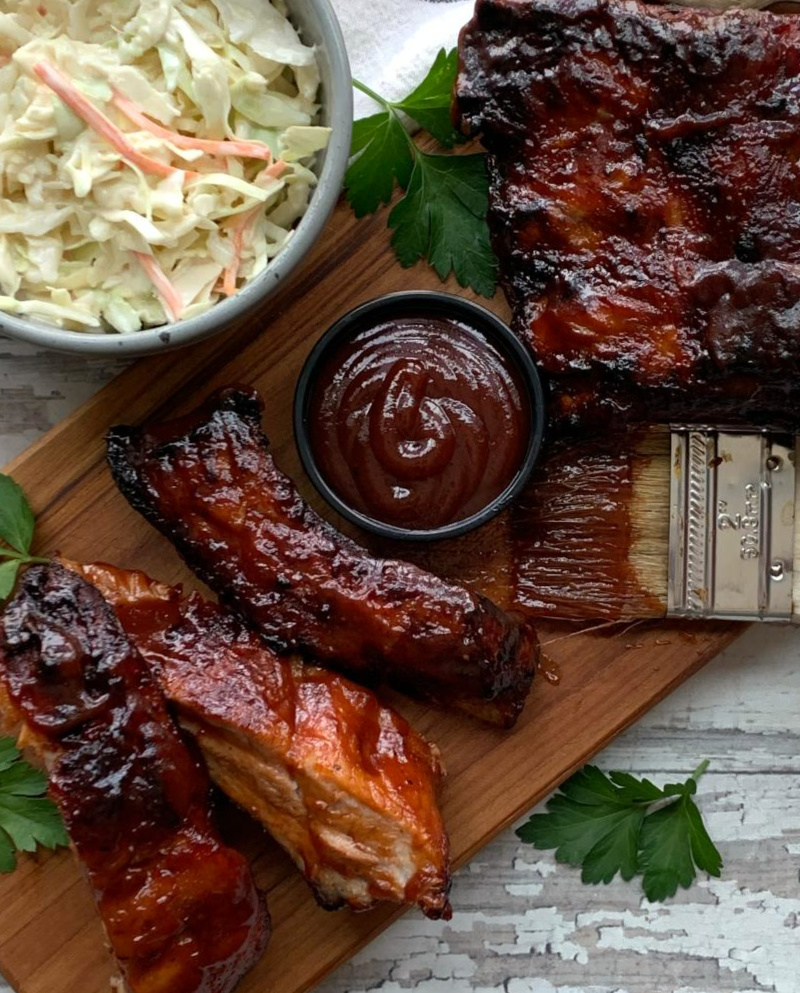 sliced air fryer bbq ribs on a cutting board with side of coleslaw