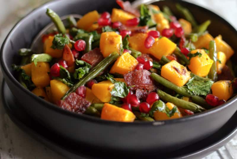black bowl with roasted green beans and butternut squash with pomegranate seeds