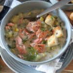 gray bowl with salmon chowder garnished with fresh dill