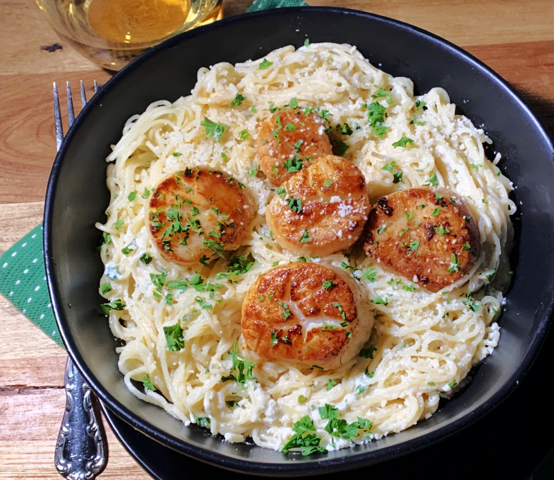 bowl of creamy angel hair pasta with pan seared scallops