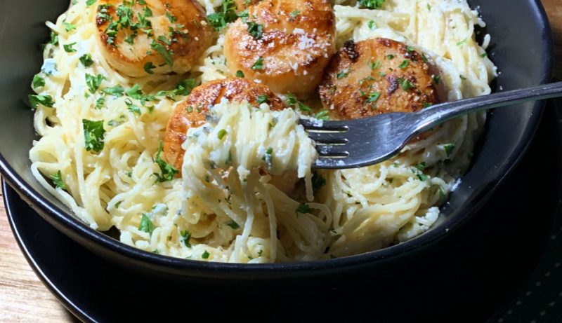 black bowl with creamy angel hair pasta and golden seared scallops