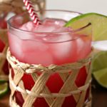 clear glass filled with pink Sea Breeze cocktail, garnished with lime slice