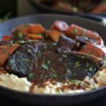 shallow black bowl with braised beef short ribs over risotto