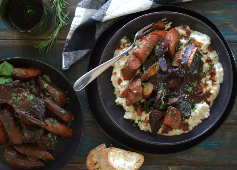 black bowl with braised beef short ribs over risotto and roasted carrots