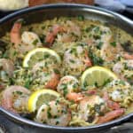 skillet with shrimp scampi with orzo garnished with parsley and lemon slices