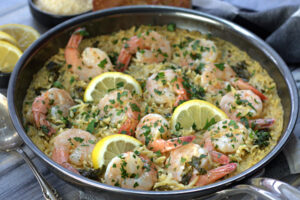 skillet with shrimp scampi with orzo garnished with parsley and lemon slices