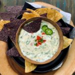 bowl of spinach queso garnished with diced tomatoes and jalapenos