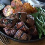 black plate with grilled steak ups, potatoes and green beans