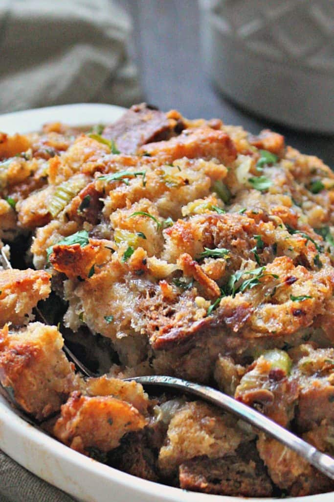sausage herb stuffing in white casserole dish garnished with parsley