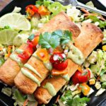 overhead view of 3 taquitos on a bed of shredded lettuce topped with fresh salsa