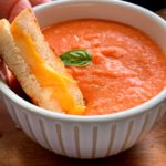 bowl of tomato soup with grilled cheese dunked into it