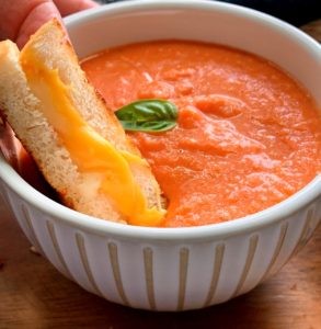 bowl of tomato soup with grilled cheese dunked into it