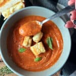 overhead view - gray bowl roasted tomato soup with spoonful of soup.