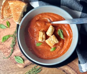 overhead view - gray bowl with roasted tomato soup and grilled cheese croutons