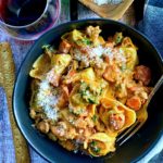 black bowl of tortellini with sausage and cream sauce