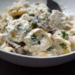 white bowl with chicken tortellini alfredo garnished with fresh parsley
