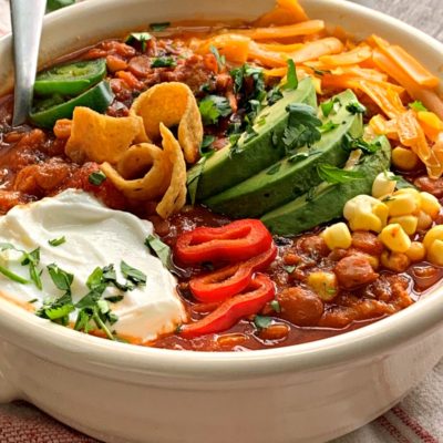 Bowl of turkey lentil chili garnished with cheese, avocado and sour cream