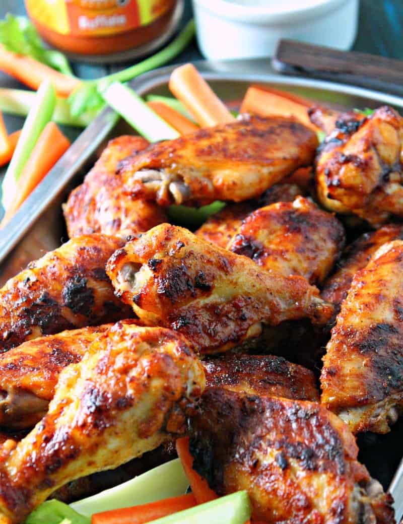 baked buffalo wings piled on platter with carrot and celery sticks