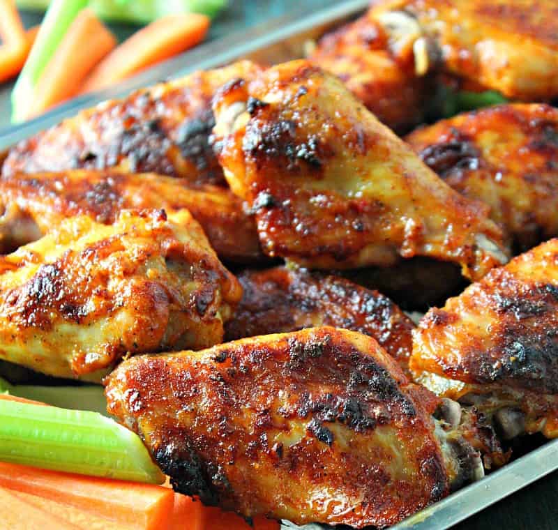 closeup of baked buffalo wings on platter with carrot and celery sticks